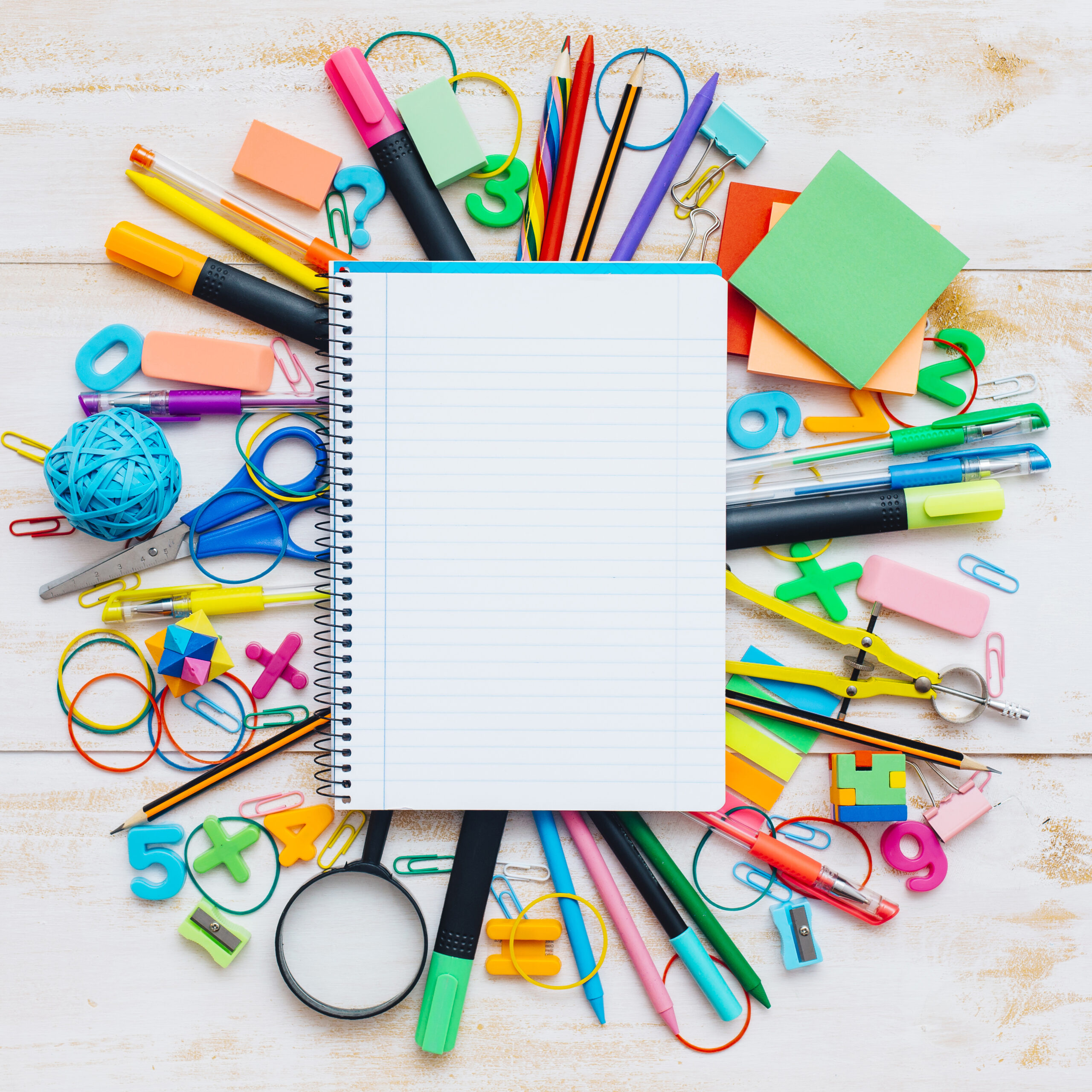 Top view of wooden desk with notebook and office supplies.